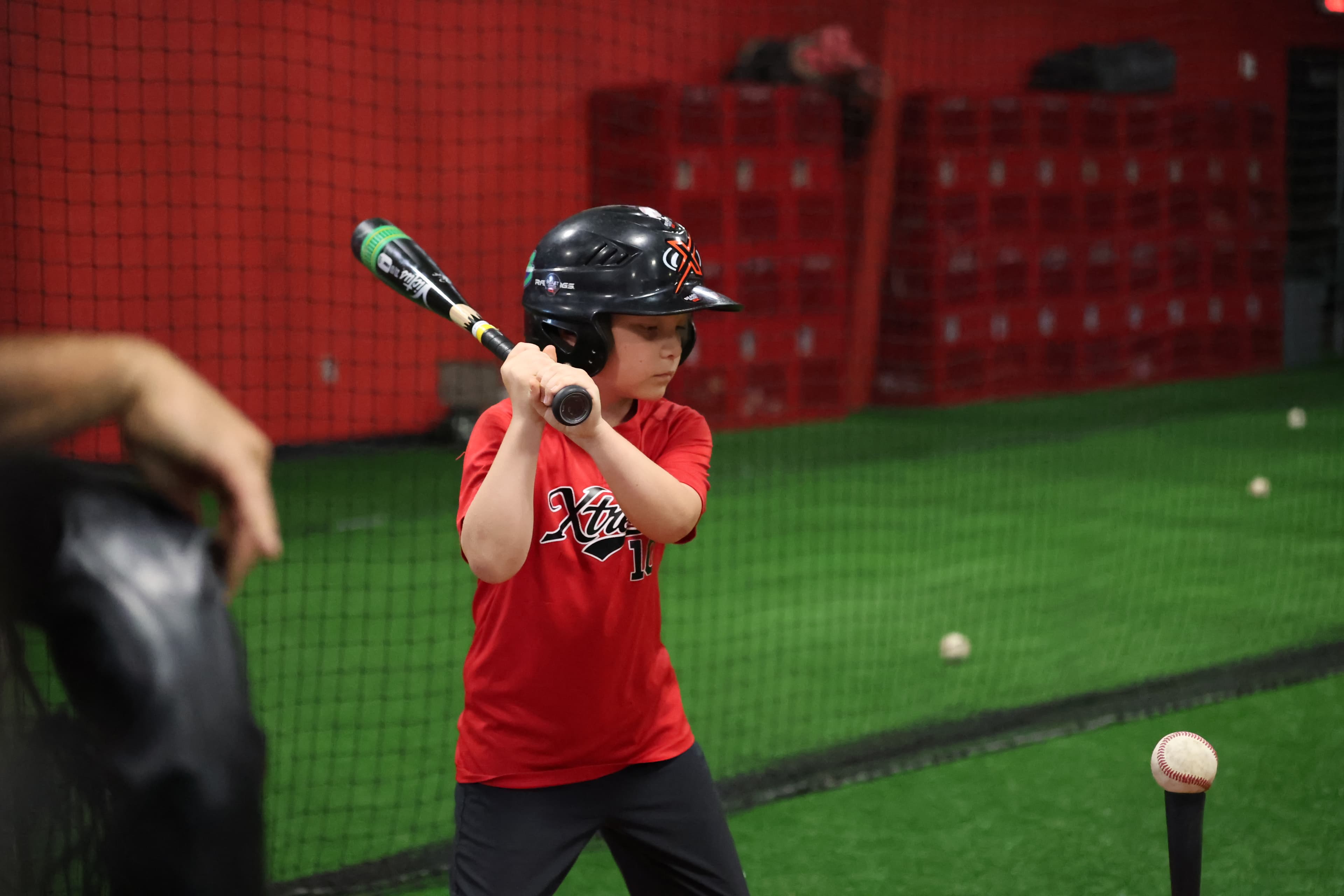 A Fall Camp camper takes a swing inside the batting cage