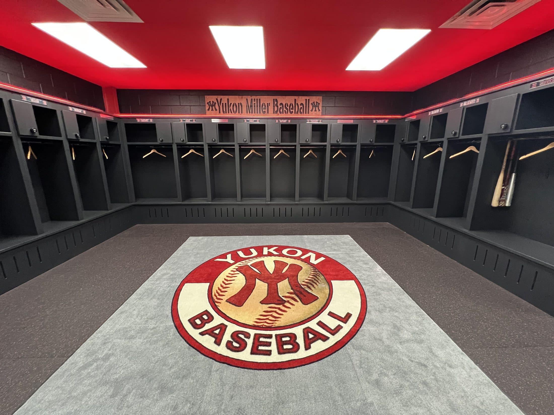 Yukon Miller Baseball clubhouse with the YM rug and empty lockers