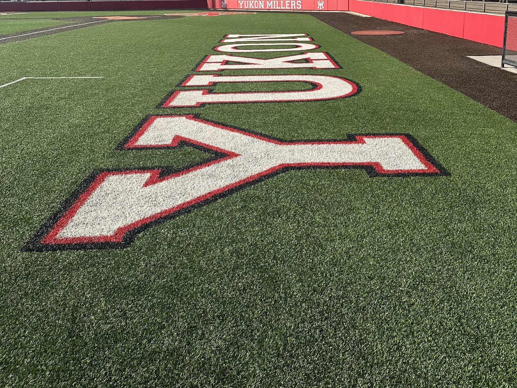 Yukon painted in the Miller Field turf, with the grandstand beyond