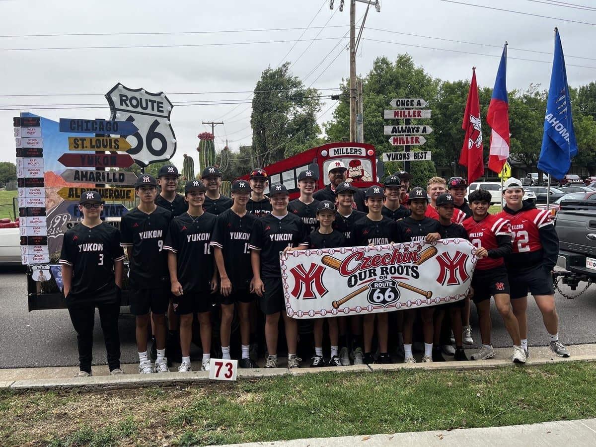 Yukon Miller Baseball players in black and red uniforms with the parade float and Czechin’ Our Roots banner