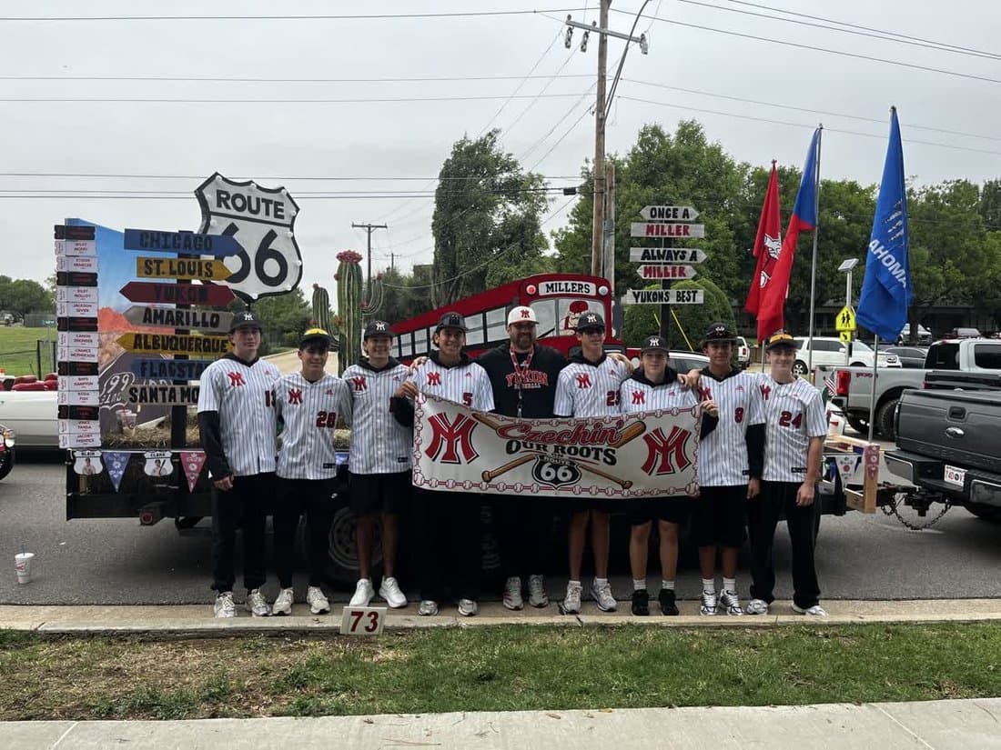 Yukon Miller Baseball players in home white pinstripes with the Czechin’ Our Roots banner