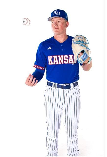 Grady Hoke in a Kansas uniform, holding a glove with a baseball in the air