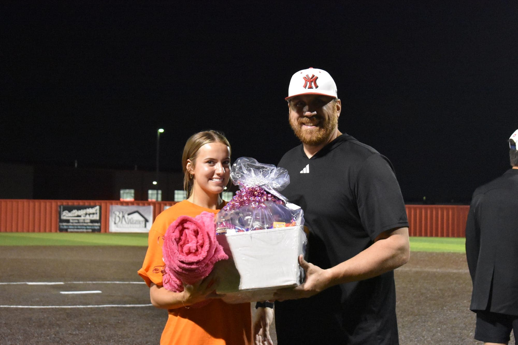 A Powder Puff participant in an orange shirt holds a pink blanket and a gift basket