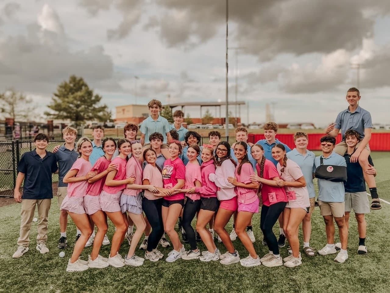 Powder Puff participants in pink and light blue pose together on the turf