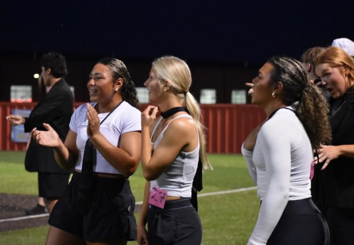 Powder Puff players clap and cheer along the sideline